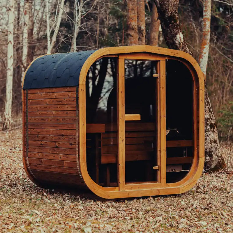 Assembled Mande Spa USA MW16 outdoor sauna with electric heater, tempered glass door, windows, Bituminous roof tiles, and metal bands in a peaceful forest setting.