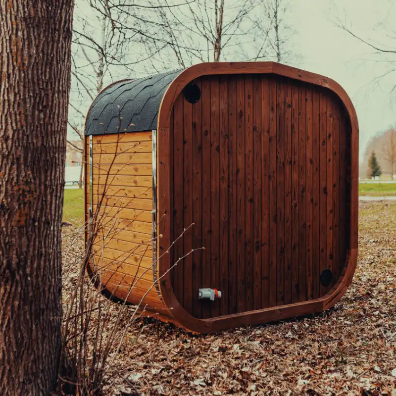 Back view of the Mande Spa USA MW12 outdoor sauna with Bituminous roof tiles in a peaceful forest setting.