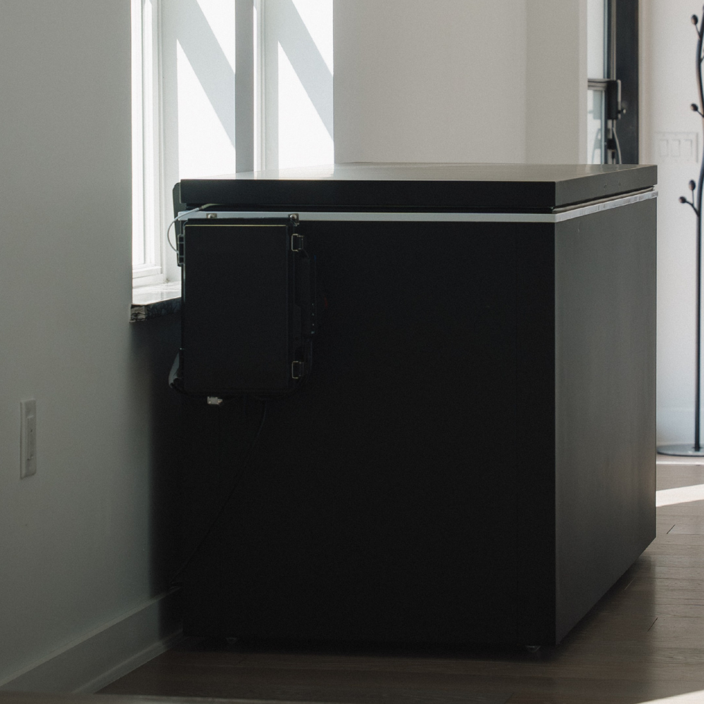Black matte Plunge Zero HardTop cold plunge tub against a wall in a room with large windows.