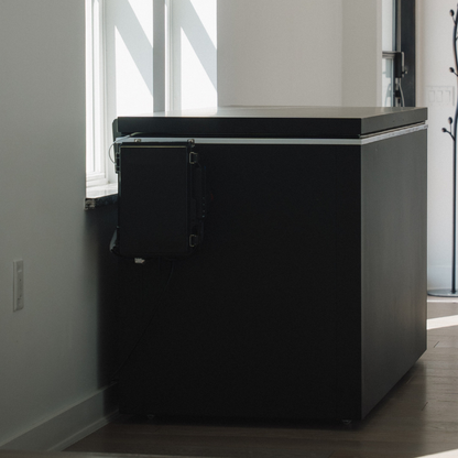 Black matte Plunge Zero HardTop cold plunge tub against a wall in a room with large windows.