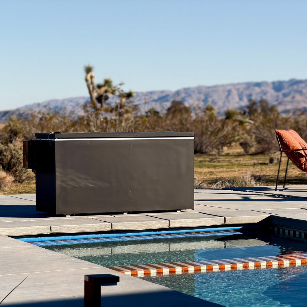Black matte Plunge Zero HardTop cold plunge tub with a pool, lounge chair, and mountainous landscape.