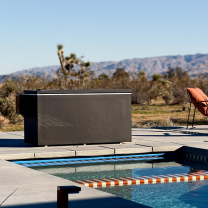 Black matte Plunge Zero HardTop cold plunge tub with a pool, lounge chair, and mountainous landscape.