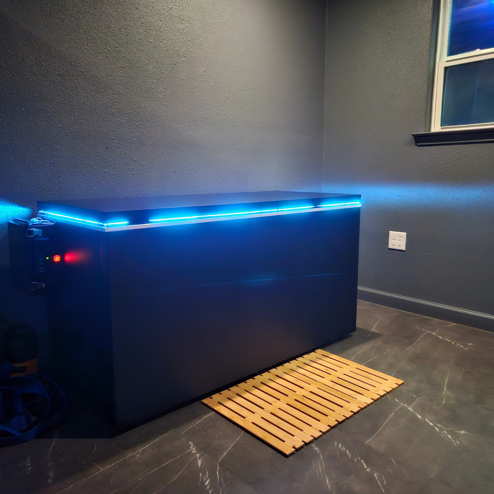 Black matte Plunge Zero HardTop cold plunge tub with blue lighting in a modern gray room.