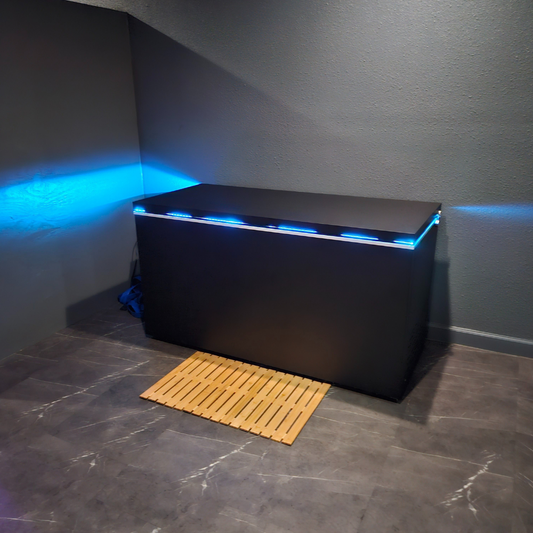 Black matte Plunge Zero HardTop cold plunge tub with blue lighting in a modern gray room.