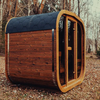 Side view of assembled Mande Spa USA MW16 outdoor sauna with electric heater, tempered glass door, windows, Bituminous roof tiles, and metal bands in a peaceful forest setting.
