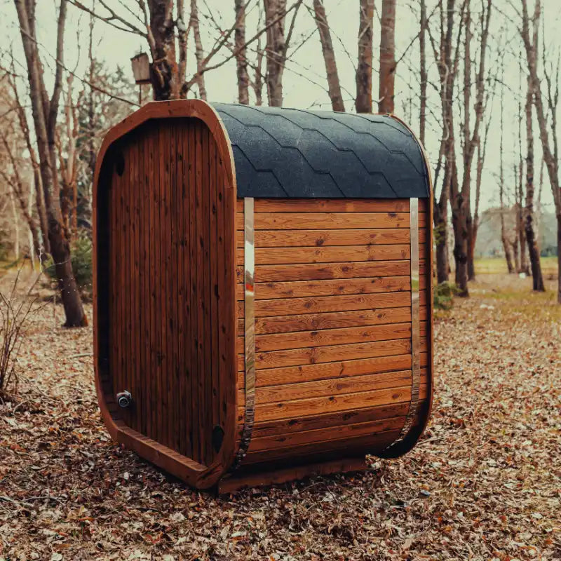 Side view of the Mande Spa USA MW12 outdoor sauna with roof shingles, metal bands, and rear exterior siding in a peaceful forest setting.