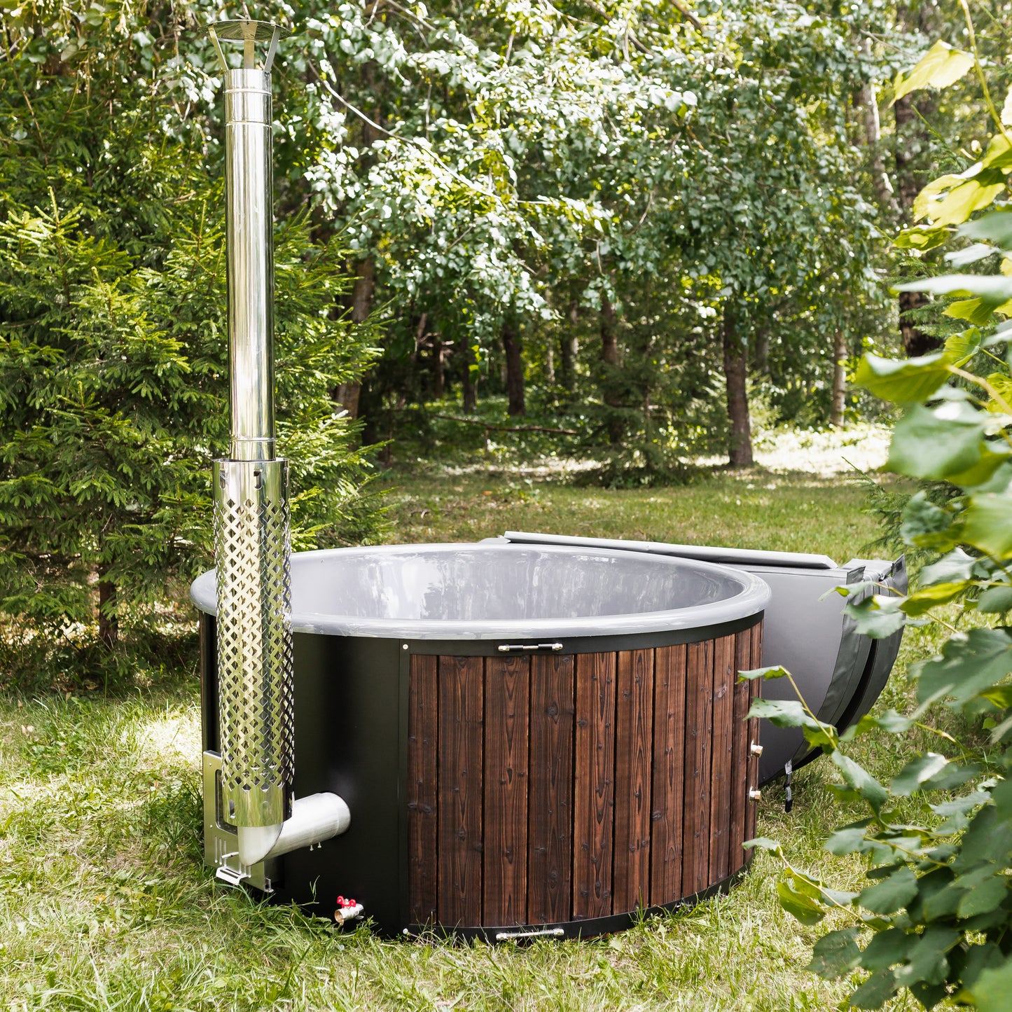 wood-fired hot tub with wooden exterior and metal chimney in a forest setting