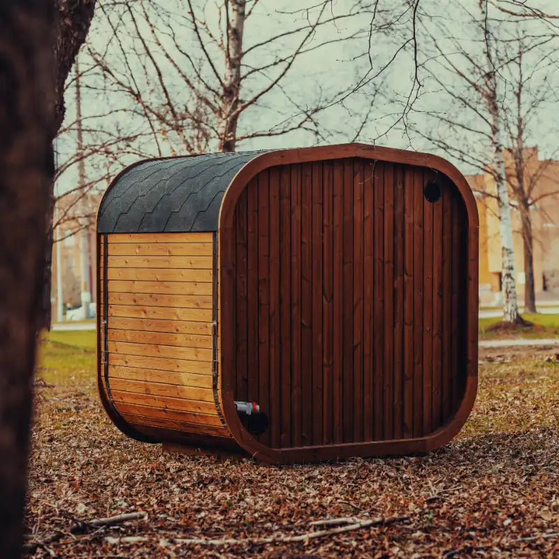 The back view of assembled Mande Spa USA MW16 outdoor sauna with tempered glass door, windows, and Bituminous roof tiles on a white background, featuring a ThermoWood® design for backyard wellness and home spa use.