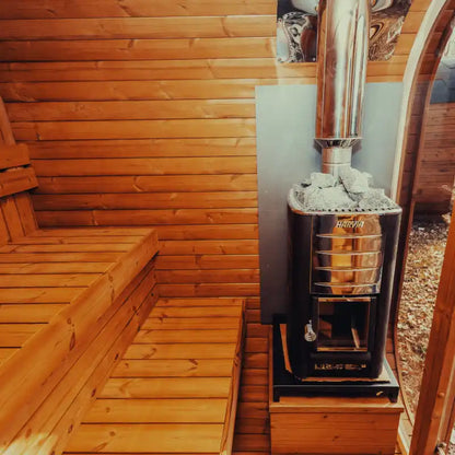 View of a wood-burning sauna heater from inside the sauna, featuring a warm wooden interior for an authentic home spa experience.
