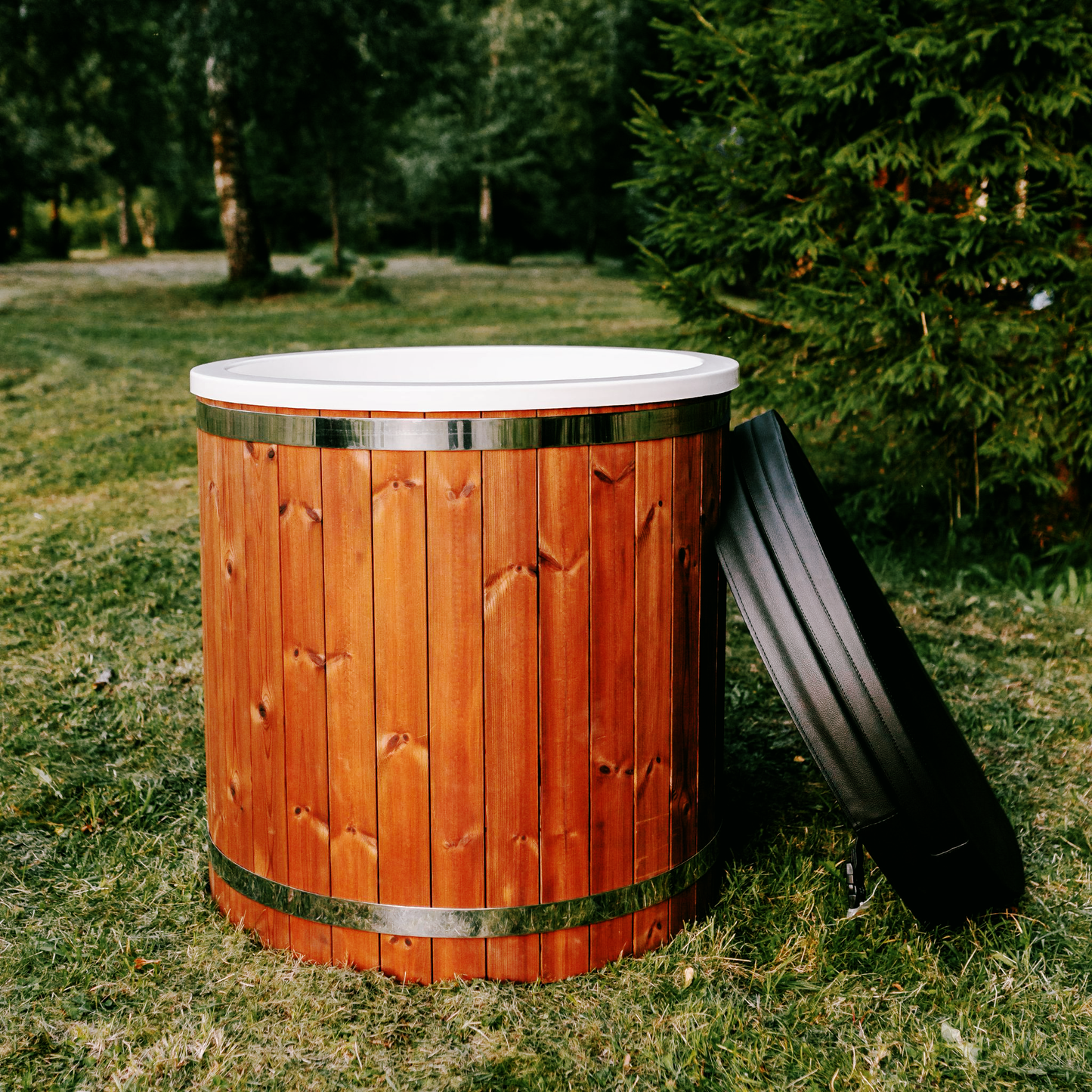 Wooden outdoor hot tub on grass with trees in the background, designed for backyard relaxation and natural wellness.